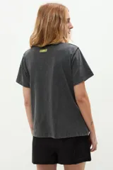 Remera negra de algodón con efecto lavado, manga corta y cuello redondo. Presenta una estampa frontal con la frase escrita en letras brillantes de estilo cursivo.