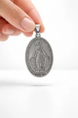 Dije ovalado de acero inoxidable con relieve de la Virgen Milagrosa y la inscripción tradicional en el borde.