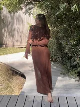 Vestido largo color crudo, de tejido de algodón fino y ligero, con escote en V y mangas largas acampanadas. Se puede usar con el escote hacia adelante o hacia atrás.