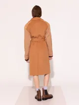 Tapado color camel con mangas y recortes tejidos al tono, con acceso delantero a través de botones.