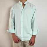 Camisa de manga larga con cuello mao, confeccionada en tela de algodón con diseño de rayas verticales finas en color verde menta y blanco. Presenta cierre frontal con botones y un pequeño bordado en el pecho.