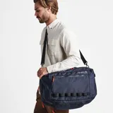 Mochila azul con detalles en negro y naranja, con dos compartimentos plegables con cierre, solapas de malla con cierre, bolsillo acolchado para computadora portátil y bolsillo oculto para pasaporte.