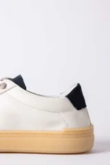 Championes urbanos de cuero blanco con suela de goma color caramelo y detalle de talón en color azul oscuro.