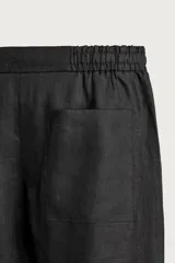 Bermuda de lino negro de corte relaxed fit, con cintura elástica ajustable mediante cordón y bolsillos frontales.