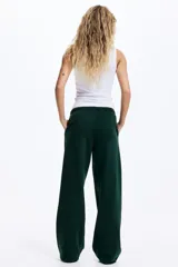 Pantalón tipo jogger de corte holgado y piernas amplias, confeccionado en felpa con interior cepillado. Presenta cintura elástica con cordón de ajuste y bolsillos laterales discretos.