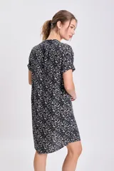 Vestido corto de manga corta y cuello mao con abertura en V, de corte suelto y estampado floral o abstracto en tonos beige sobre fondo negro.