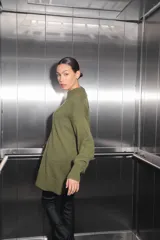 Sweater verde oliva de tejido de punto con cuello polo, mangas largas y corte oversize. Presenta un parche con monograma en la espalda.