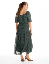 Vestido midi de gasa estampada con diseño de hojas, escote en V cruzado y mangas cortas fluidas. Presenta cintura elastizada con lazo ajustable y falda con volados escalonados que aportan movimiento. Incluye forro interno a tono.