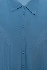 Camisa de manga larga con cuello solapa, confeccionada en tejido fluido. Presenta detalle de jaretas verticales en el frente y cierre frontal con botones forrados al tono.