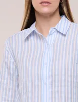 Camisa de algodón calado, con diseño a rayas en tonos celestes y blancos, cuello con solapa, cierre frontal con botones y mangas largas con puños abotonados.