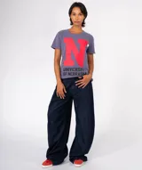 Camiseta de manga corta color marrón con efecto lavado y desgastado. Presenta una gran letra 'T' morada estampada en el centro, con el texto 'UNIVERSITY OF TENESSEE' debajo en color negro. Incluye apliques decorativos en el área del pecho.