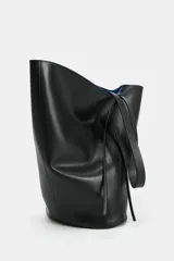 Maxi bolso de hombro de piel en color negro con interior azul y tiras colgantes en el lateral.