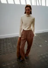 Camisa satinada de color blanco marfil, con diseño recto, cuello alto y manga larga.