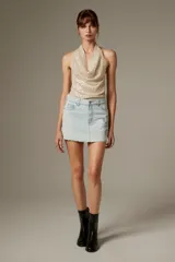 Top de poliéster revestido de lentejuelas color beige, con cuello buche y diseño sin mangas al cuerpo.