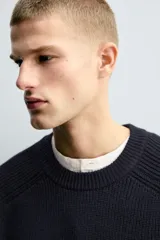 Jersey de punto con diseño boxy fit, cuello redondo y manga larga. Presenta una textura acanalada y acabados en rib en cuello, puños y ruedo.