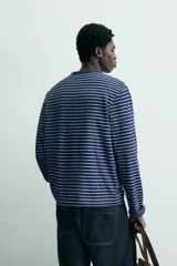 Camiseta de manga larga con cuello redondo y efecto lavado. Presenta un patrón de rayas horizontales finas en azul marino y blanco/beige.