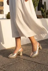 Zapato destalonado de cuero color dorado metalizado, con taco ancho y punta fina.