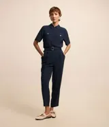 Pantalón zanahoria de mujer confeccionado en tela airflow color azul marino, con trabillas en la cintura, cinturón con hebilla, pliegues y elástico en la espalda.