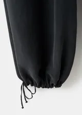 Pantalón largo estilo balloon de tiro medio, confeccionado en mezcla de lyocell y poliéster, con cintura elástica, bolsillos laterales y bajo con goma elástica.