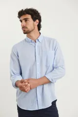 Camisa de manga larga confeccionada en una mezcla de algodón y lino, con cuello abotonado, cierre frontal de botones y un bolsillo en el pecho.