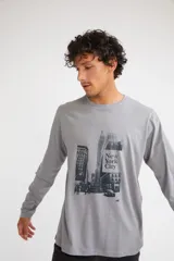 Remera de manga larga color gris melange, con cuello redondo y estampado gráfico en blanco y negro de la ciudad de Nueva York en el frente.
