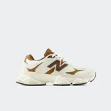Championes New Balance 9060, de diseño moderno y voluminoso, combinan tonos beige, blanco y marrón. Presentan una parte superior de malla transpirable con superposiciones de ante, el característico logotipo "N" en los laterales en marrón y una suela esculpida distintiva.