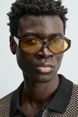 Polo de manga corta con cuello solapa y cierre frontal de dos botones. Tejido de punto con textura de rombos en tonos negro y beige, con ribetes negros en cuello, mangas y bajo.