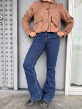 Jean de tiro alto con corte acampanado, confeccionado en denim azul oscuro con costuras en contraste.