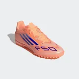 Championes de fútbol Adidas modelo F50 Club, color naranja con tres franjas y estampado 'F50' en azul. Presentan una suela de caucho con tacos bajos para césped artificial.