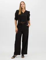 Blusa de algodón semitransparente con diseño floral bordado a tono. Presenta escote en V, cierre frontal con botones y mangas al codo ligeramente abullonadas. Incluye detalles de encaje calado estilo macramé en los puños y en el ruedo con terminaciones en ondas.