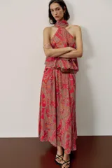 Falda larga de corte fluido con estampado paisley en tonos rojos, naranjas y celestes. Cuenta con cintura elástica y viene con un cinturón de cuero marrón con hebilla metálica dorada.