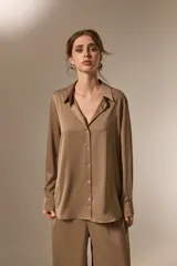 Camisa de poliéster con acabado satinado, de corte holgado, cuello camisero clásico, cierre frontal con botones y mangas largas con puños.