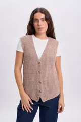 Chaleco de punto con lurex en color crudo, sin mangas, con escote en V y cierre frontal con botones.