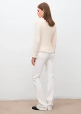 Chaqueta de tweed color crema con cuello redondo, cierre frontal con botones y dos bolsillos de parche delanteros. Presenta terminaciones deshilachadas y forro interior.