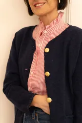 Camisa de corte clásico con estampado de rayas verticales rojas y blancas, cuello camisero con volados y cierre frontal de botones.