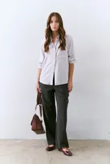 Camisa blanca de manga larga con cuello clásico, cierre de botones frontal y bolsillo de parche en el pecho.