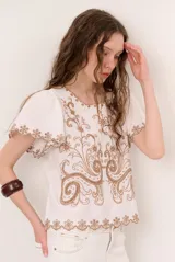 Blusa blanca de manga corta con bordados en tono marrón en el frente, mangas y ruedo, y escote redondo.