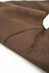 Bolso tipo hobo confeccionado en gamuza marrón, con diseño slouchy, asa corta de cuero y argollas metálicas plateadas.