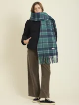 Bufanda de tejido suave con diseño a cuadros en tonos beige y amarillo neón. Presenta flecos en los extremos y una etiqueta de la marca Rusty.