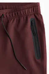 Pantalón jogger deportivo de corte ajustado, confeccionado en tejido funcional con tecnología DryMove para absorción de sudor. Presenta cintura elástica con cordón de ajuste y bolsillos laterales con cierre sellado.