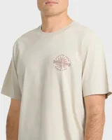 Remera Billabong de manga corta y corte regular, color beige, con gran estampado gráfico en la espalda que incluye el texto "Billabong", la ilustración de una quilla de tabla de surf y un sol estilizado.