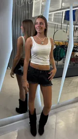 Short de jean negro de tiro bajo, con ruedo desflecado y detalle de estrella grande con glitter plateado en el bolsillo trasero derecho. Incluye etiqueta de cuero sintético en la parte posterior.