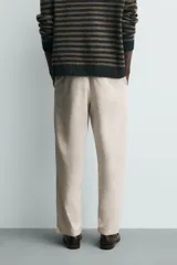 Pantalón de corte relajado confeccionado en una mezcla de algodón y lino. Presenta cintura elástica con cordón ajustable, bolsillos laterales y bolsillos traseros de vivo.