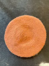 Boina tejida en crochet de lana merino pura, con diseño circular y color naranja.