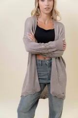 Cardigan tejido liviano color beige con efecto brillante y calados en las mangas. Diseño abierto y corte relajado.