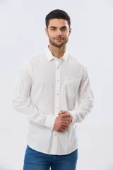 Camisa de lino de manga larga en color beige, con cuello camisero, cierre frontal de botones y un bolsillo ojal en el pecho.