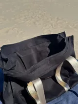 Bolso tipo tote bag negro con detalles dorados en las asas y en el logo.