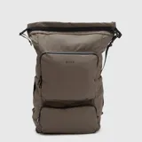 Mochila urbana de diseño roll-top en color marrón topo, con múltiples compartimentos frontales con cierre, bolsillos laterales y correas ajustables. Incluye compartimento acolchado para laptop, panel trasero transpirable y sistema de enganche para maletas.