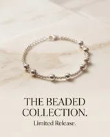 Pulsera de acero con baño de plata y esferas deslizantes decorativas intercaladas en una fina cadena.