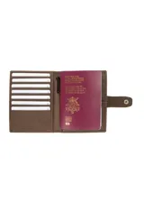 Porta pasaporte y billetera de cuero color marrón con cierre de tira y broche a presión. Presenta un diseño rectangular con costuras decorativas horizontales y un sutil logo grabado en la esquina inferior derecha.